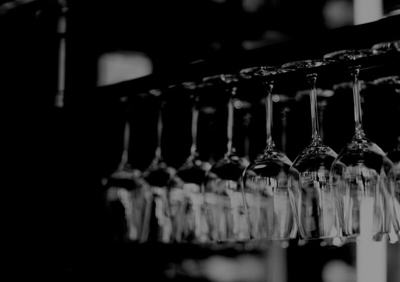 a black and white photo of wine glasses hanging from a bar top