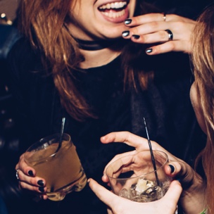 two women laughing while holding drinks
